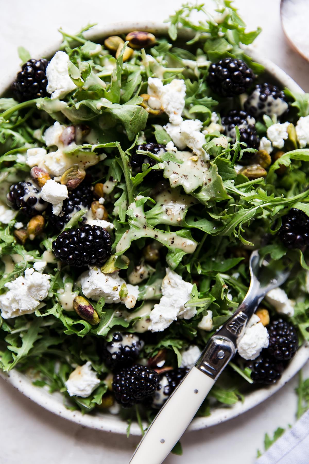 Blackberry, goat cheese Salad With Honey Mustard Dressing on a plate with a fork
