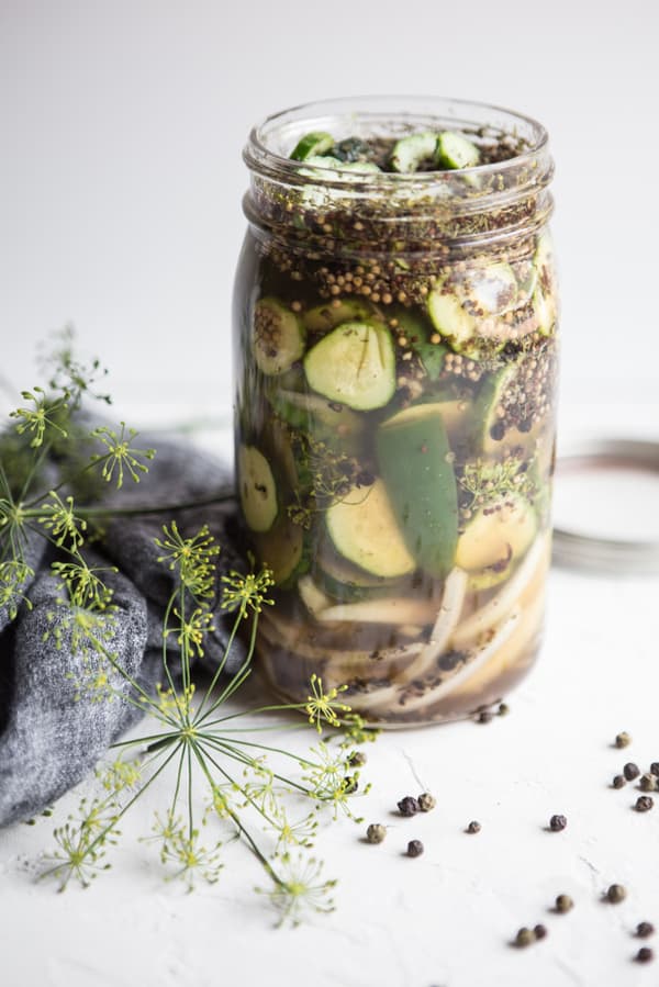 Jar of homemade quick pickles with fresh dill flowers next to it