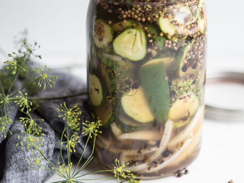 Jar of homemade quick pickles with fresh dill flowers next to it