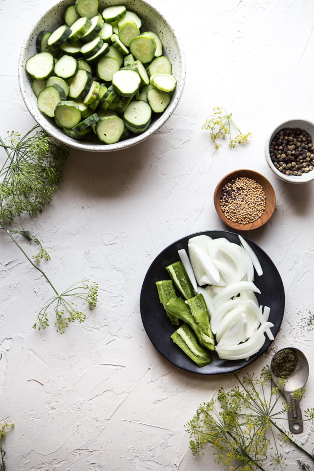 ingredients for easy homemade pickles; cucumber slices, onions, jalapenos, peppercord, coriander and dill
