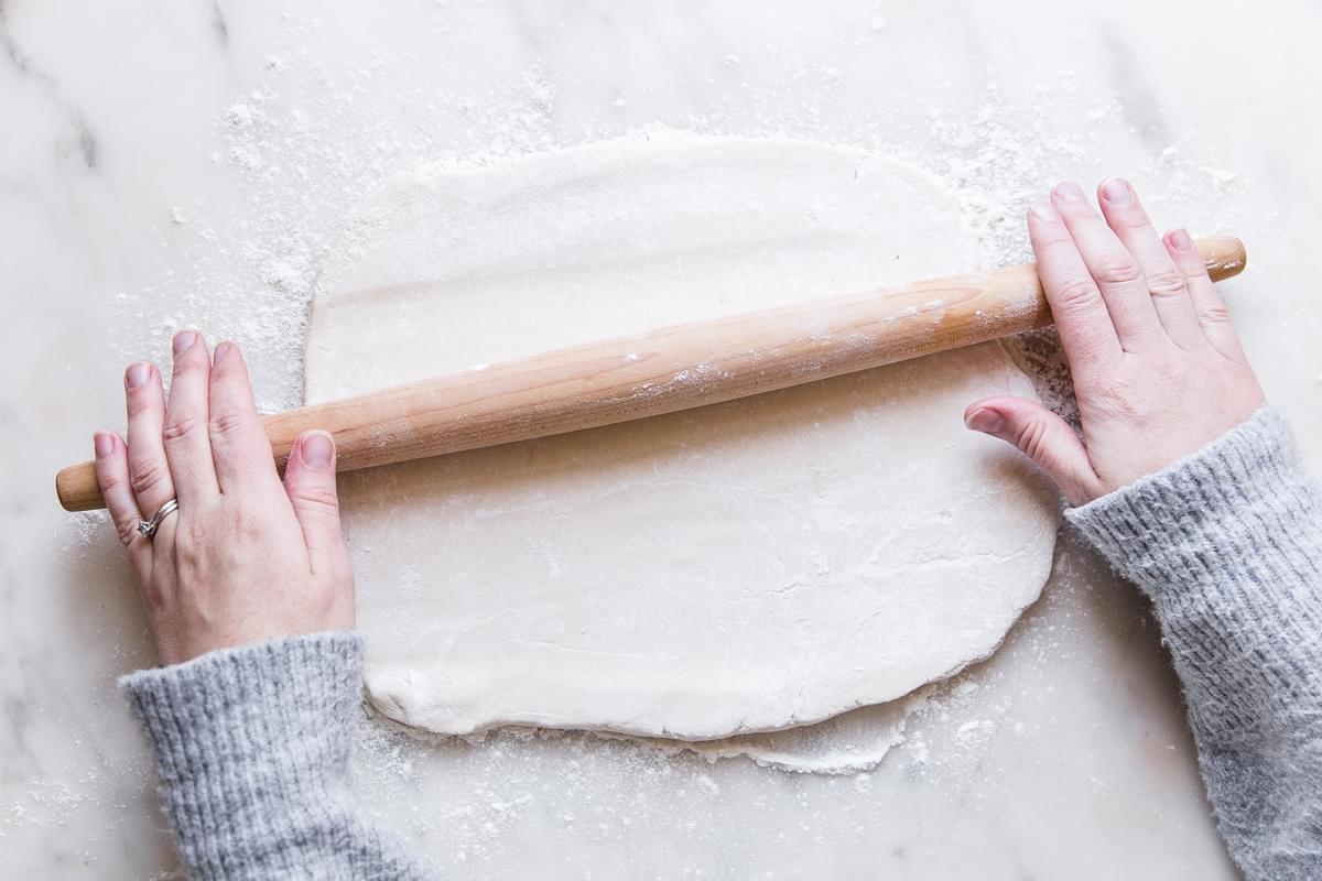 Hands rolling out dough for Sour Cream Sugar Cookies