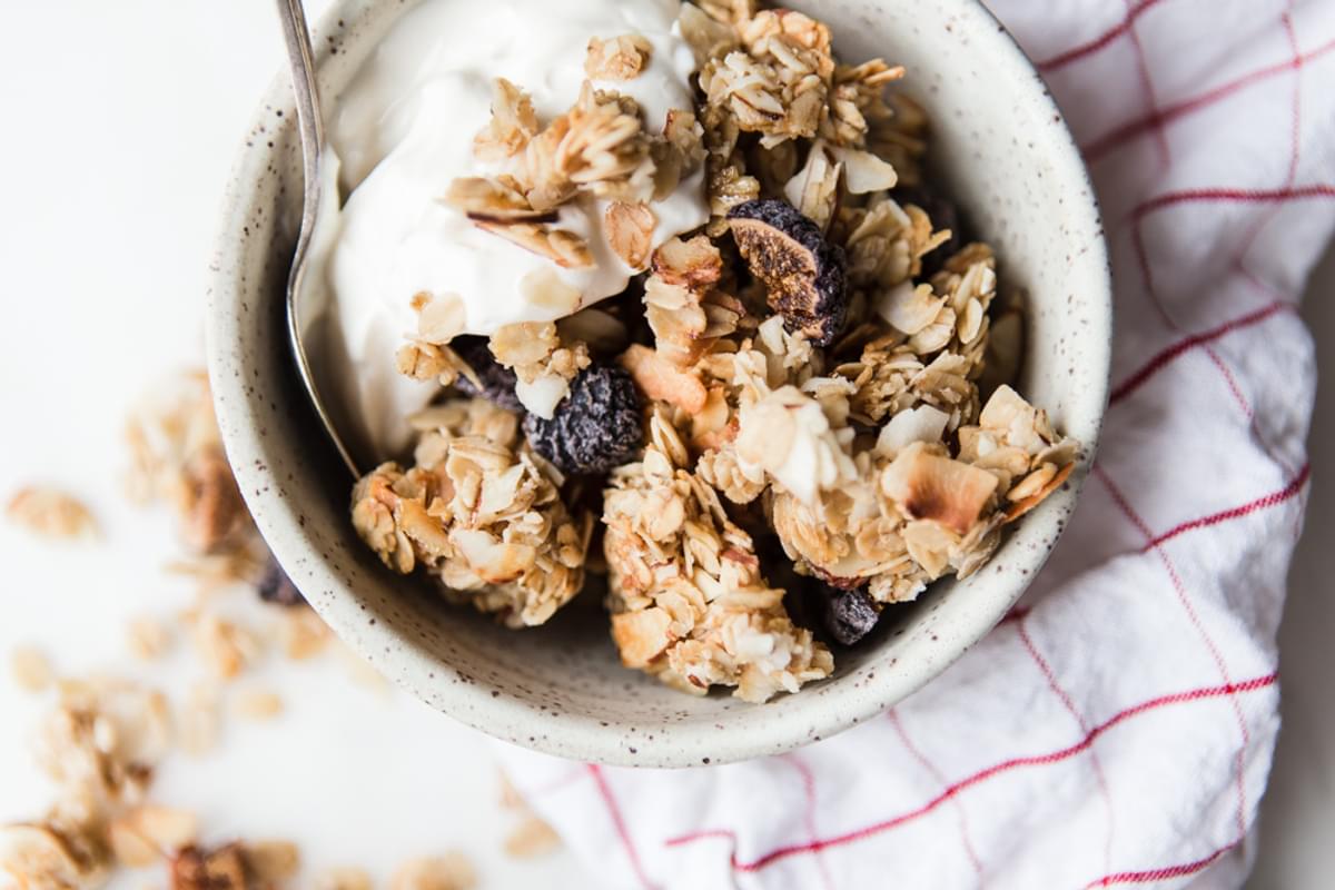 homemade vanilla Granola with Figs, Almonds and Coconut with yogurt in a bowl with a striped linen napkin.
