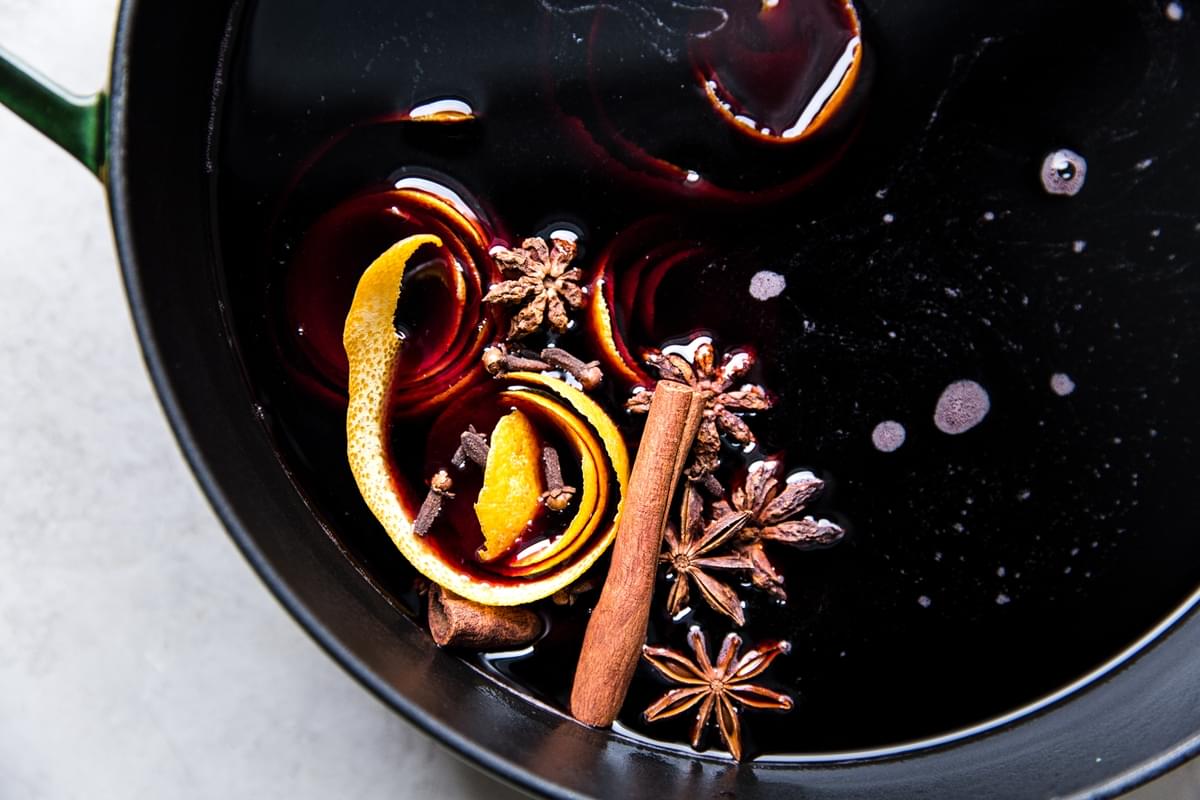 a pot of mulled red wine made with, fresh orange juice, orange peels, brown sugar, star anise, cloves & cinnamon sticks