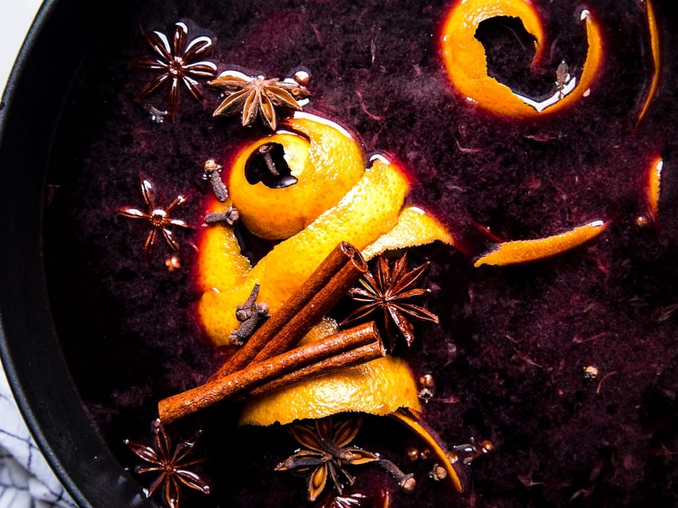 Large pot of warm mulled wine with orange peels, cinnamon and star anise.