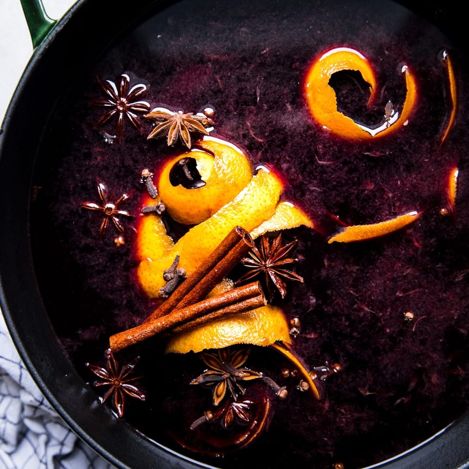 a pot of mulled wine made with red wine, fresh orange juice, orange peels, brown sugar, star anise, cloves & cinnamon sticks