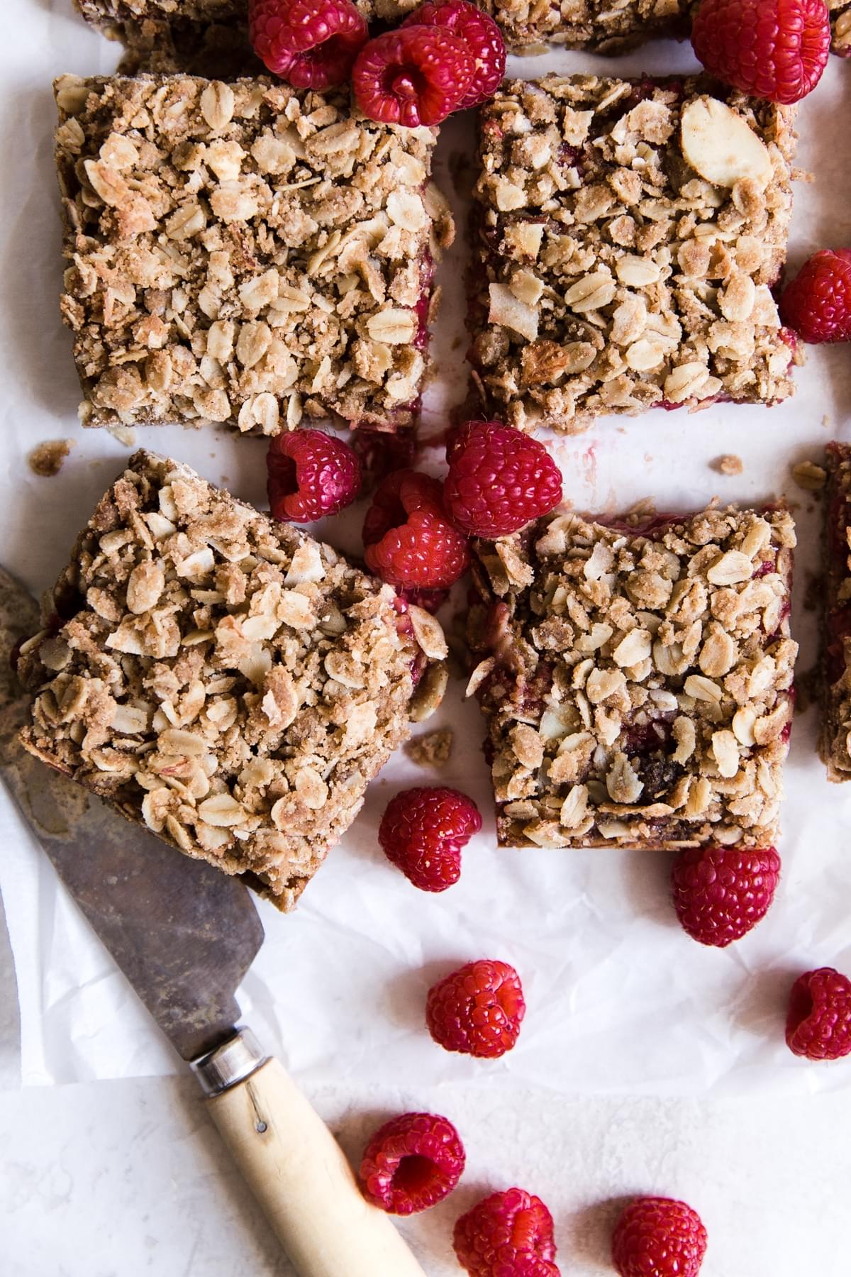 4 slices Raspberry Oatmeal Breakfast Bars with almonds and coconut with a knife
