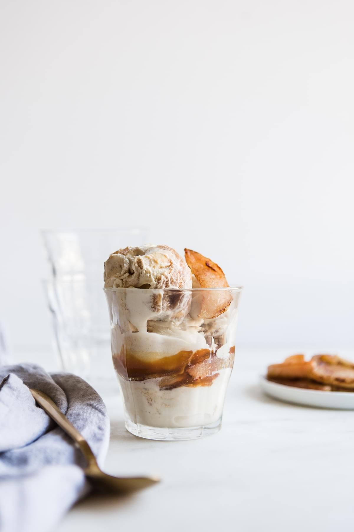 A salted caramel apple sundae in a cup with a spoon and linen