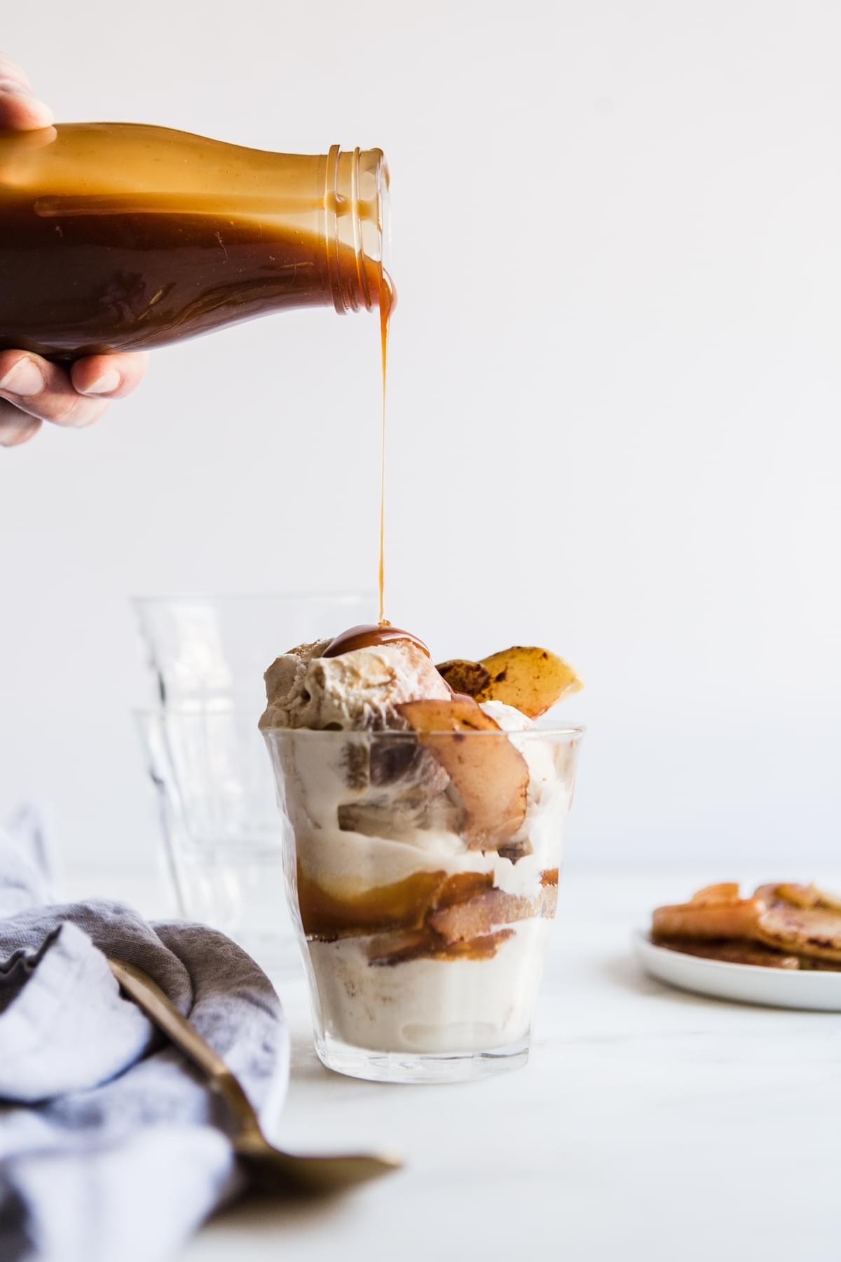 homemade salted caramel sauce being poured over an cinnamon roasted apple sundae in a cup