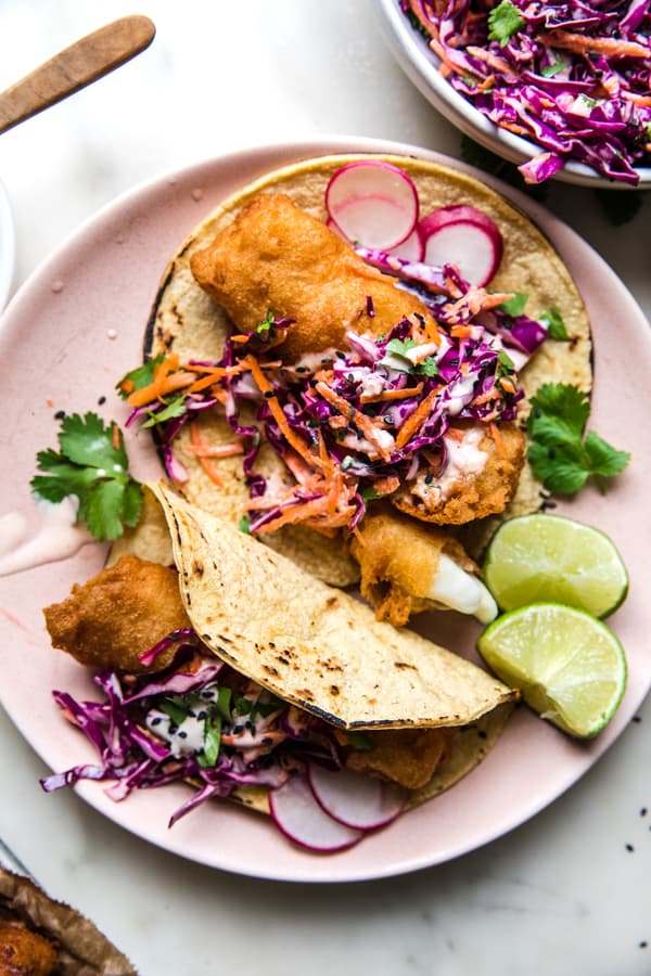 Beer-Battered Fish Tacos with sesame slaw on corn tortillas on a plate