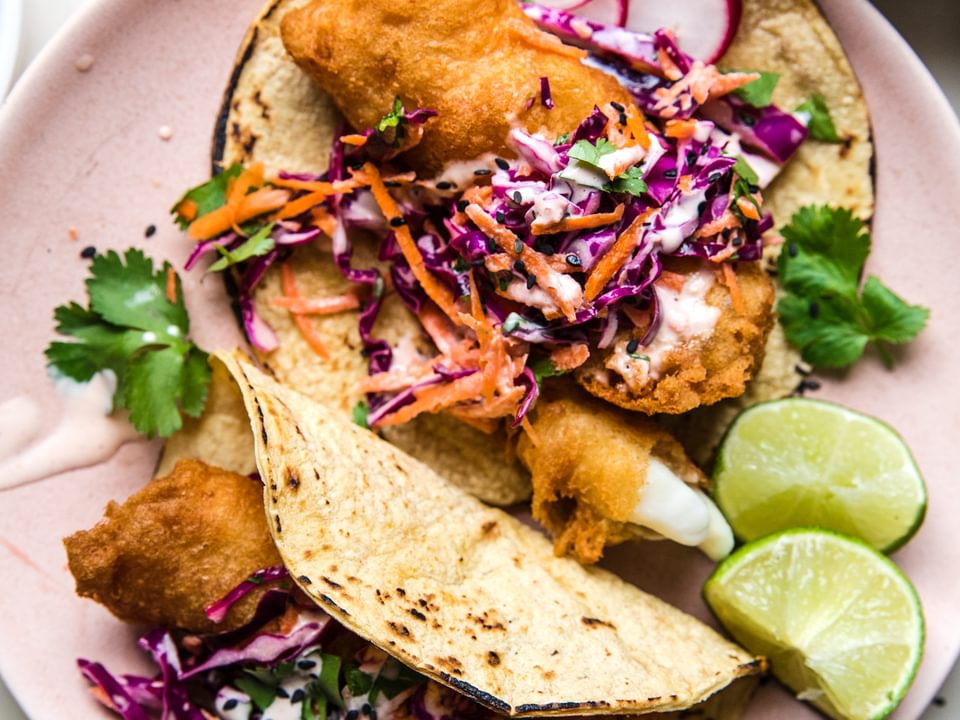 Beer-Battered Fish Tacos with sesame slaw on corn tortillas on a plate