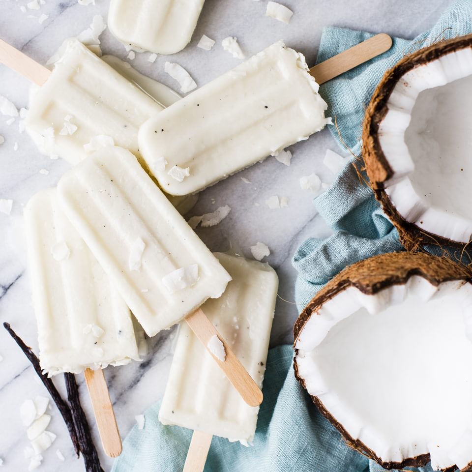 Coconut Cream Popsicles With Vanilla Bean And Malibu Rum next to an open coconut