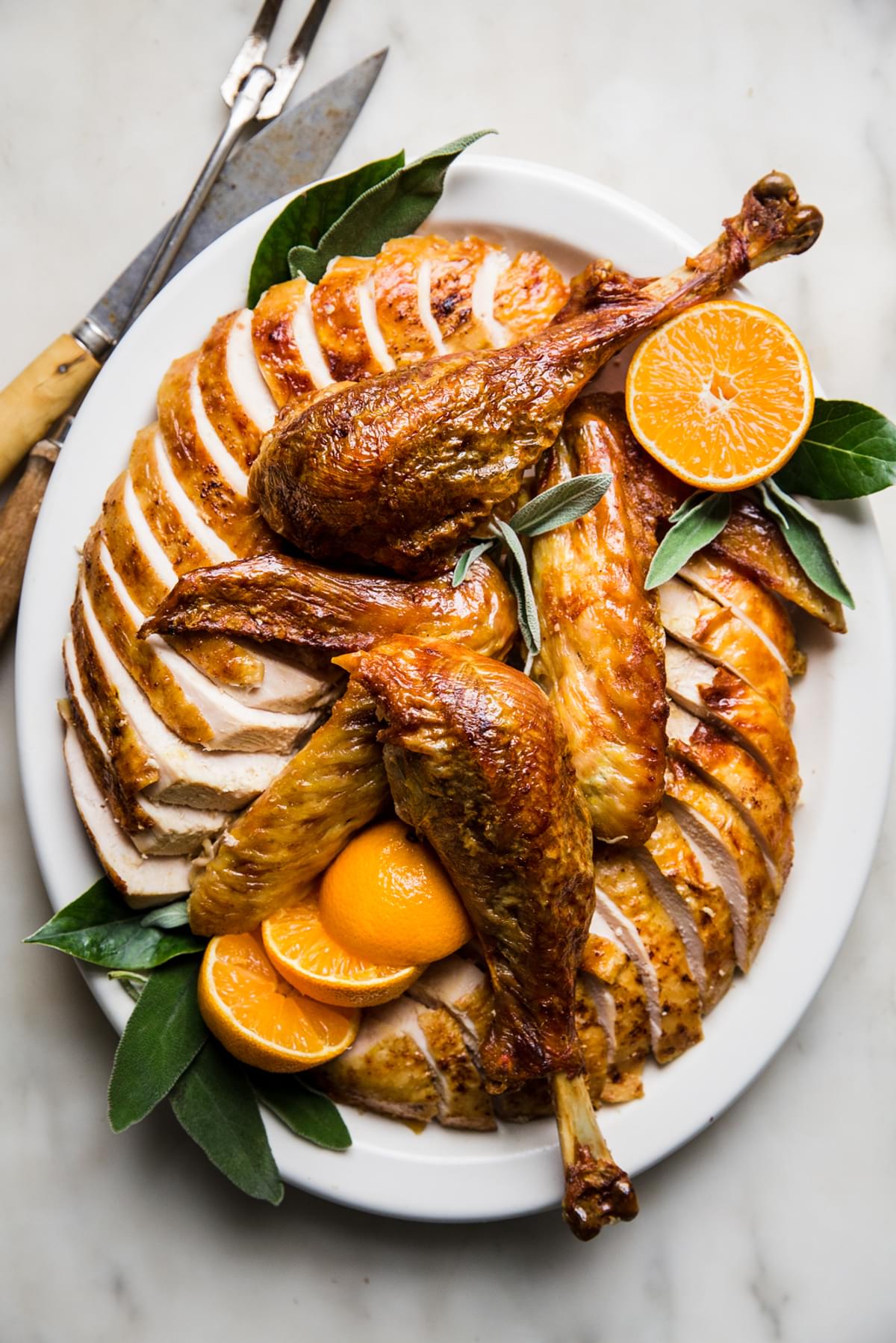 best roast turkey recipe with oranges and sage butter on a serving platter with sage leaves