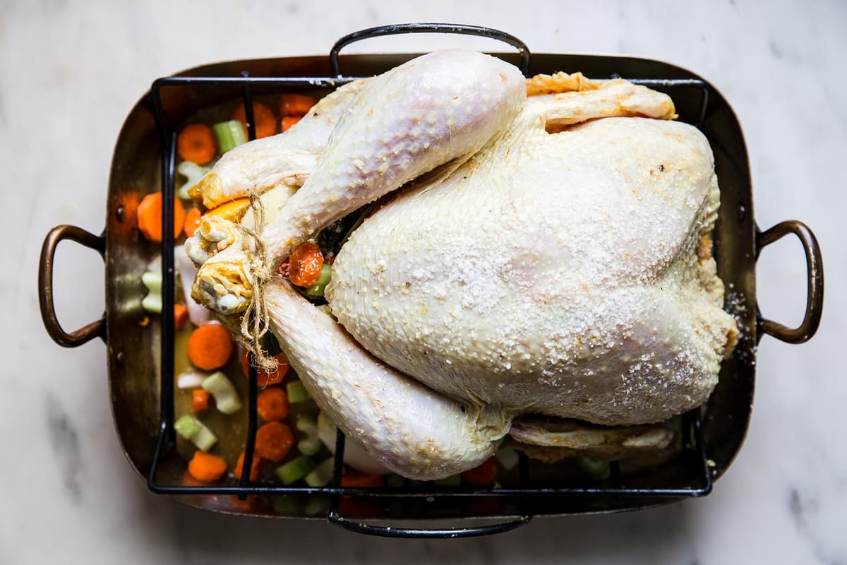 raw dry brined turkey with oranges and sage butter in a roasting pan