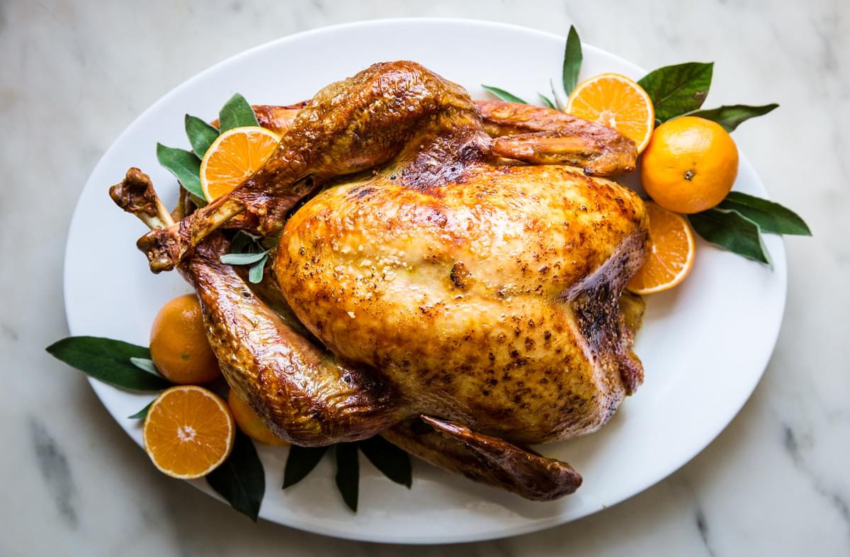 best roast turkey recipe with oranges and sage butter on a serving platter with sage leaves