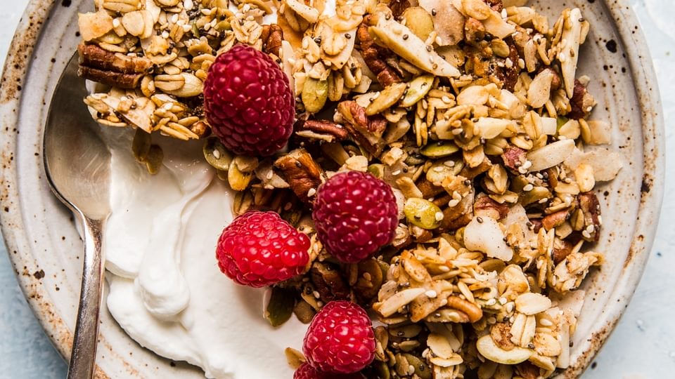nuts and seeds granola with oats,  yogurt and fresh raspberries in a bowl