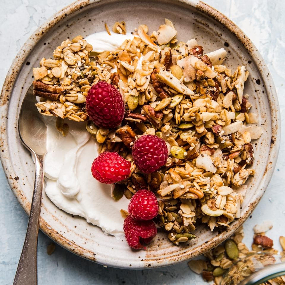 nuts and seeds granola with oats,  yogurt and fresh raspberries in a bowl