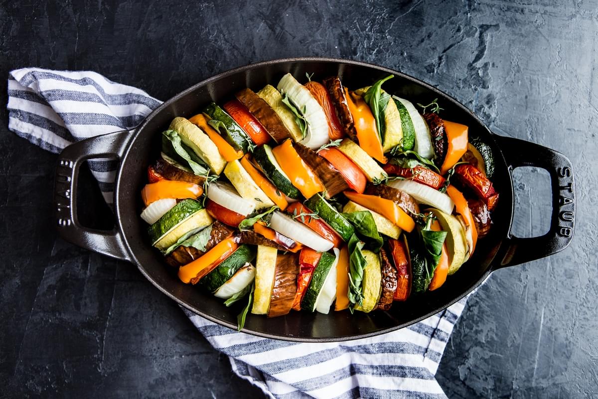 Ratatouille in a cast iron baking dish with a striped linen