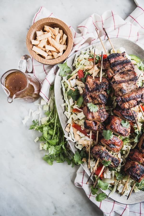 Asian Chopped Salad with Hoisin Marinated Pork Kabab on a platter with dressing