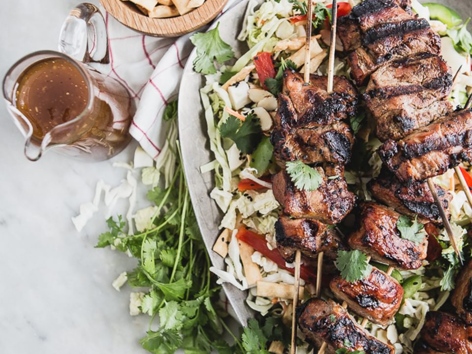 Asian Chopped Salad with Hoisin Marinated Pork Kabab on a platter with dressing