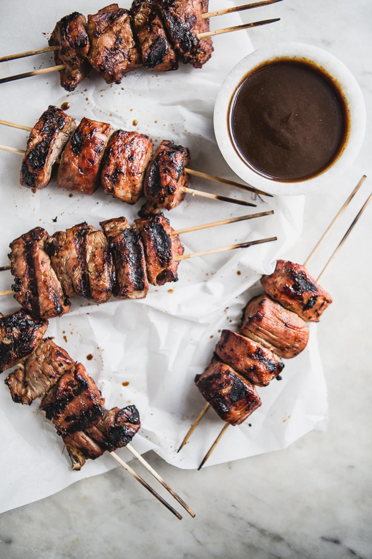 Hoisin Marinated Pork Kababs on parchment paper with a bowl of hoisin sauce