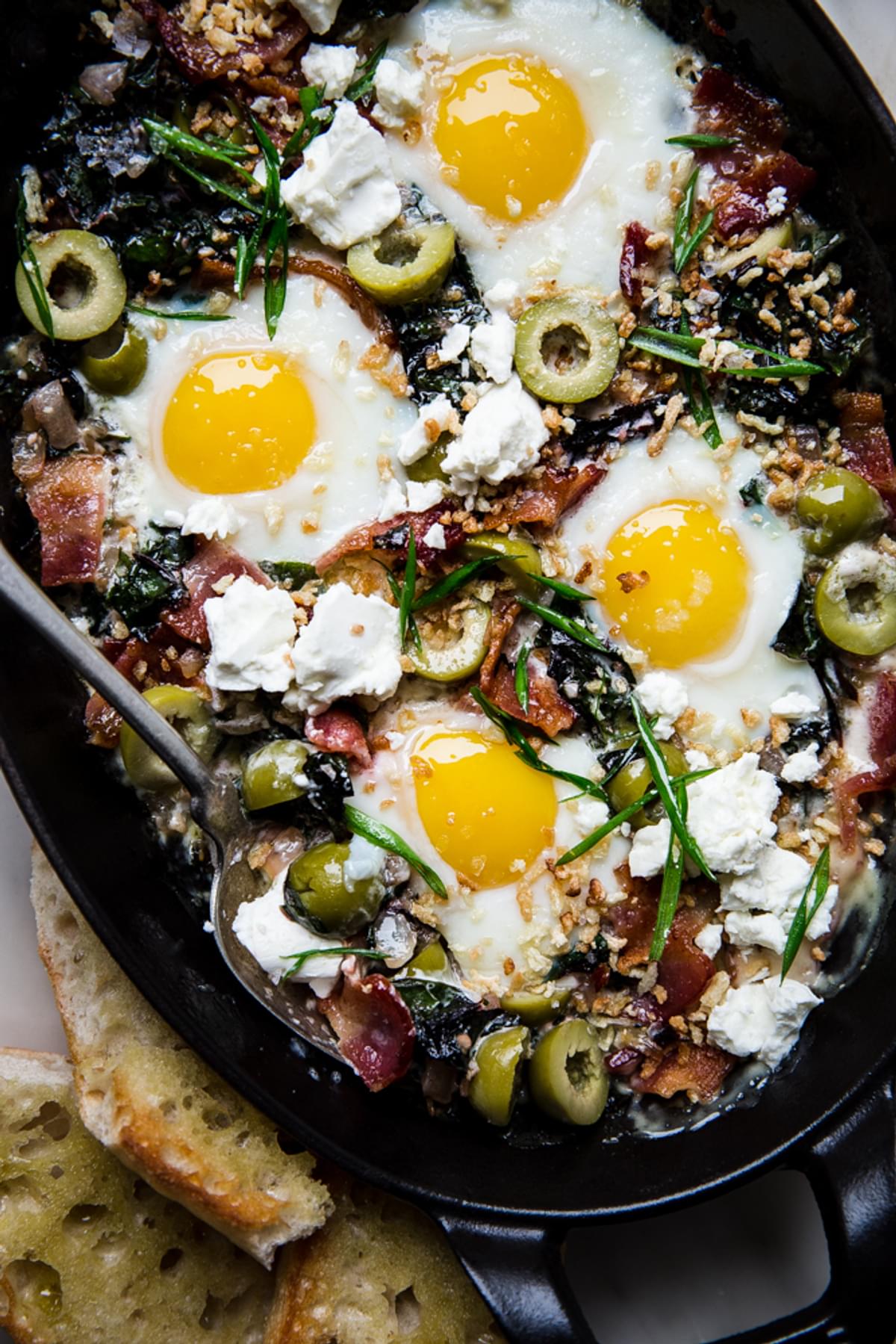 Baked Eggs with Swiss Chard and Green Olives cream and serves with crusty bread