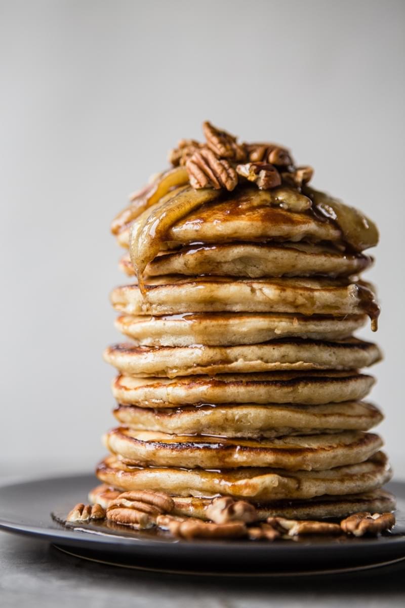 Stack of banana pancakes with caramelized bananas, pecans and syrup