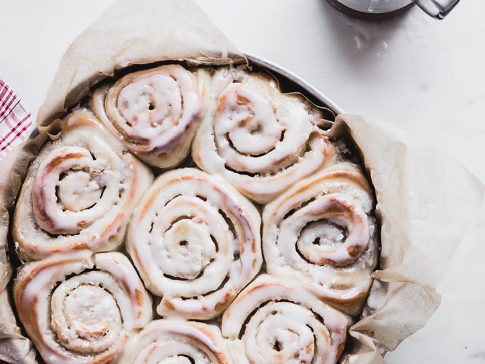 Cardamom Rolls with Almond Glaze in a baking dish with extra glaze on the size