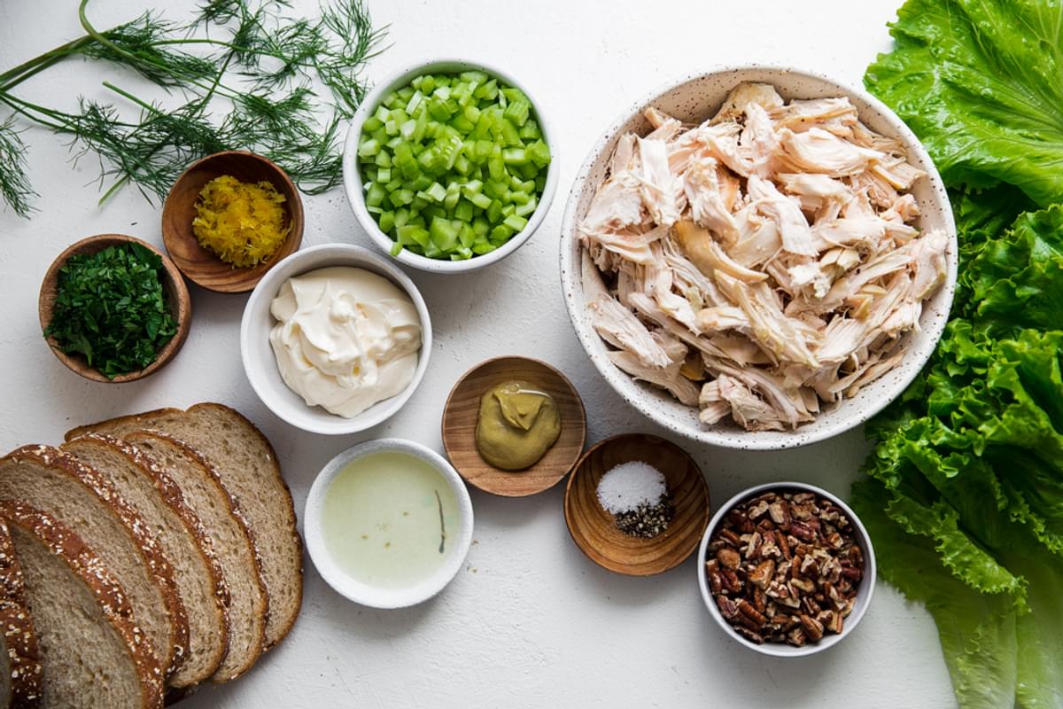 ingredients for chicken salad sandwiches. bread, shredded chicken, lettuce, lemon juice, tarragon, celery, pecans