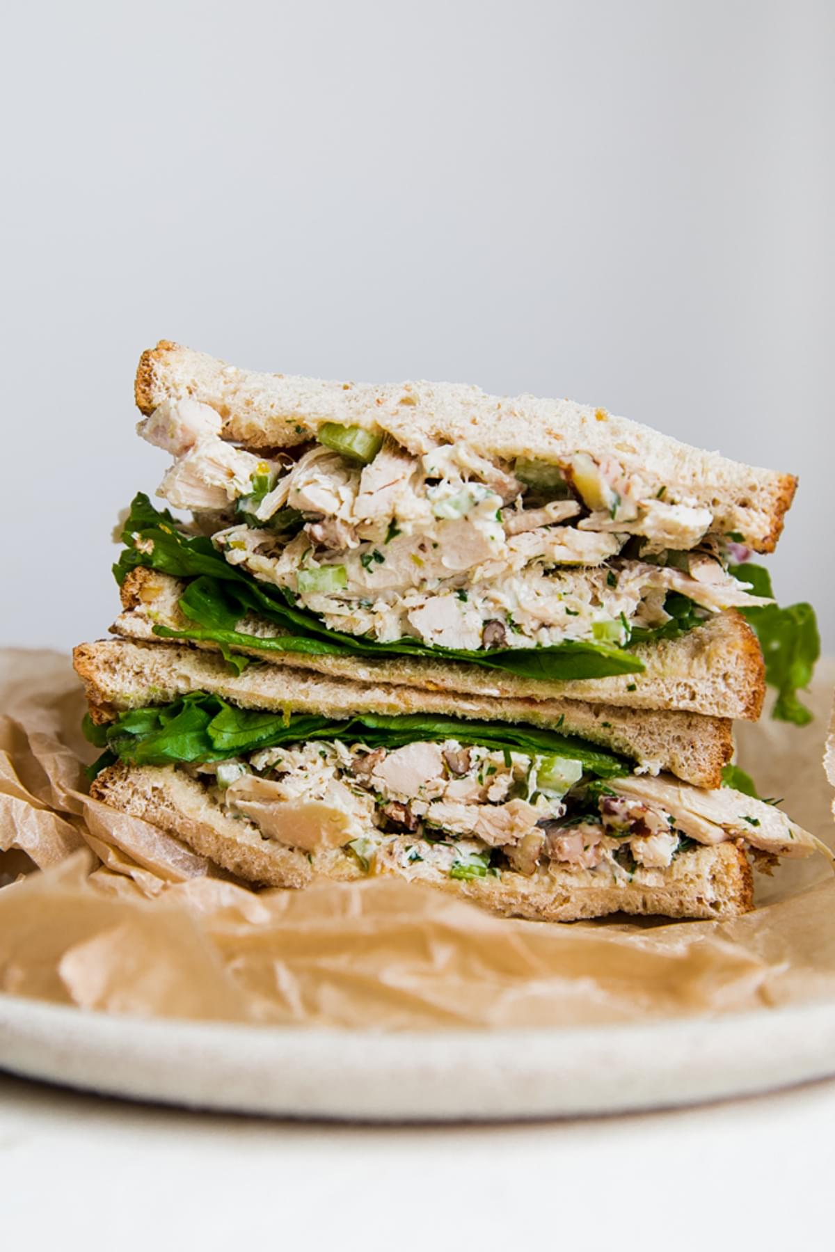 chicken salad recipe made and stacked on a plate with shredded chicken, lettuce, lemon, tarragon