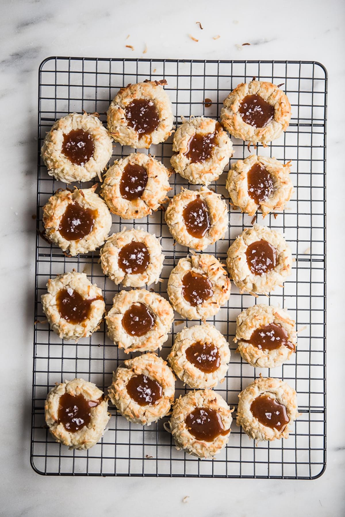 Coconut Thumbprint Cookies with Salted Caramel sauce on a cooling rack