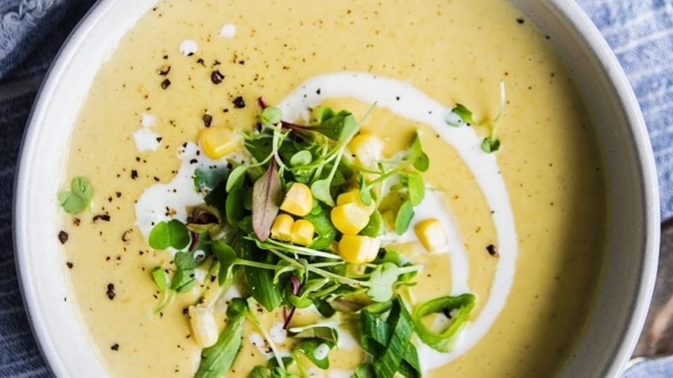 a bowl of Corn and Leek Bisque with cream and a spoon