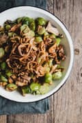 Creamy Brussels Sprouts with Wild Mushrooms and fried shallots in a bowl with a serving spoon
