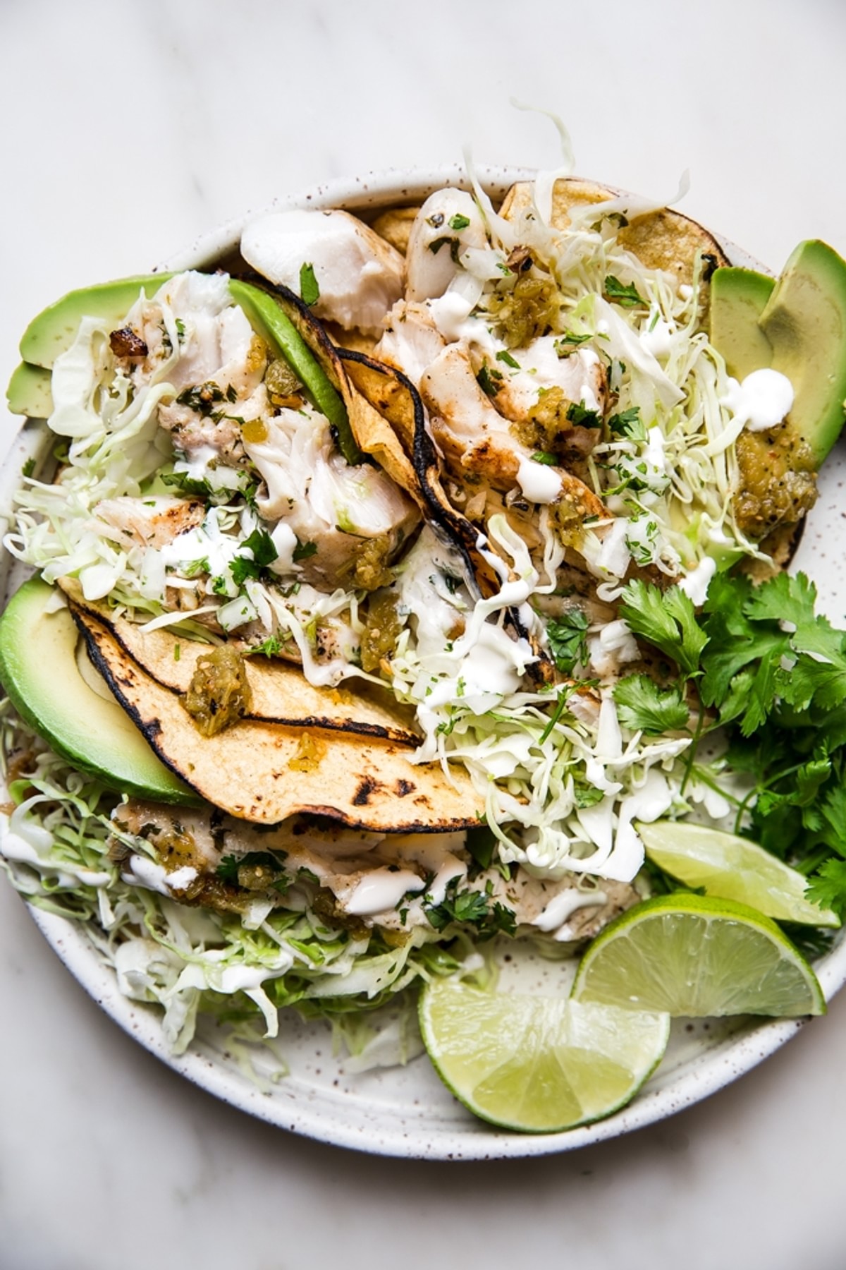 Grilled Tilapia Tacos on a plate with cabbage, limes and avocado