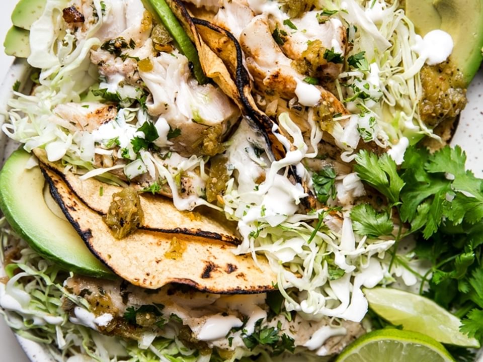 Grilled Tilapia Tacos on a plate with cabbage, limes and avocado