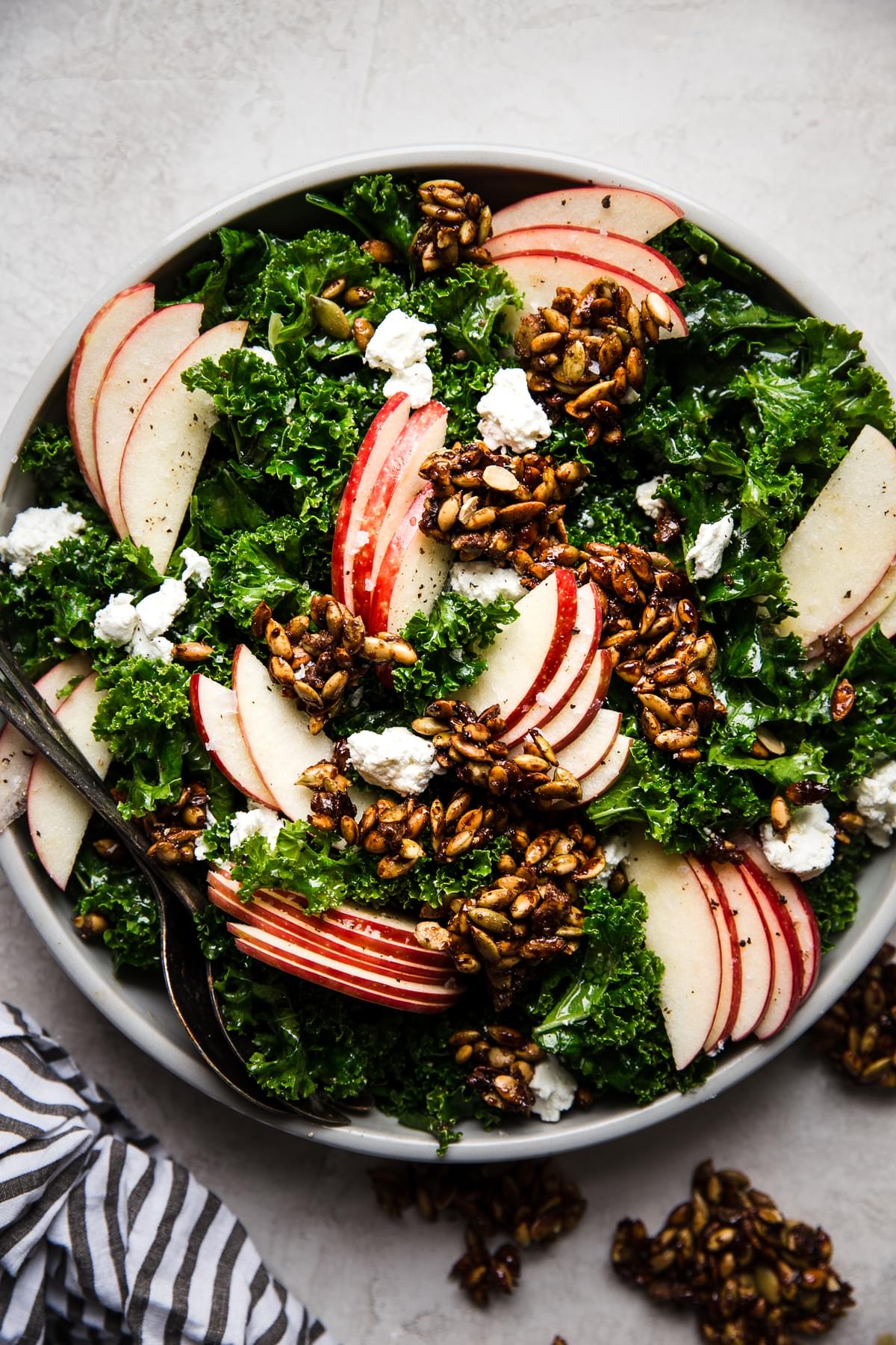 Kale Salad with Pumpkin Seed Clusters, apple slices, goat cheese and a creamy maple dressing in a bowl
