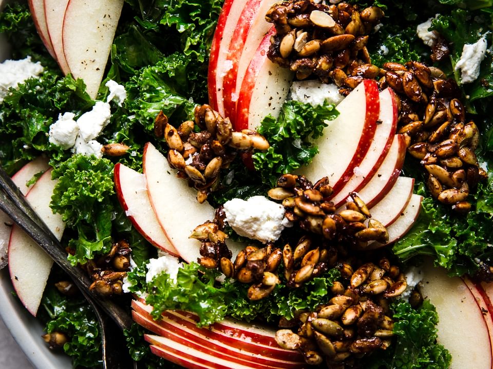 Kale Salad with Pumpkin Seed Clusters and apple slices in a bowl