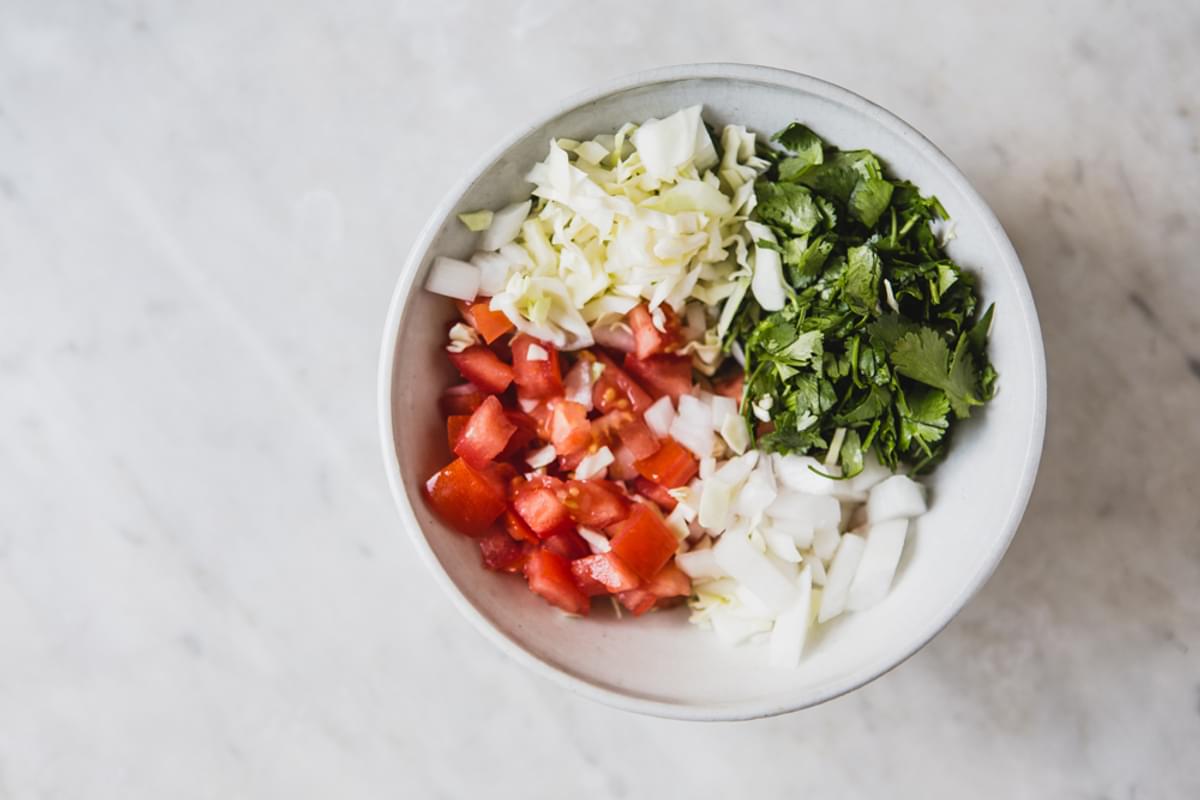 diced tomatoes, shredded cabbage, died onion and roughly chopped cilantro in a bowl