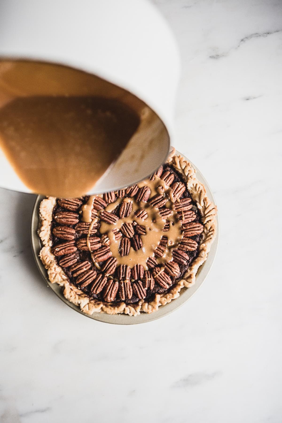 caramel being poured over a pecan pie