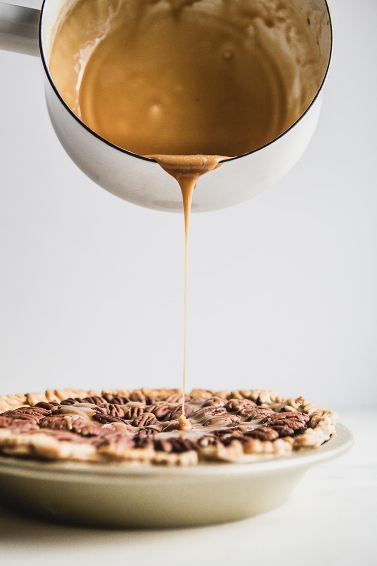 caramel sauce being poured over an apple pie