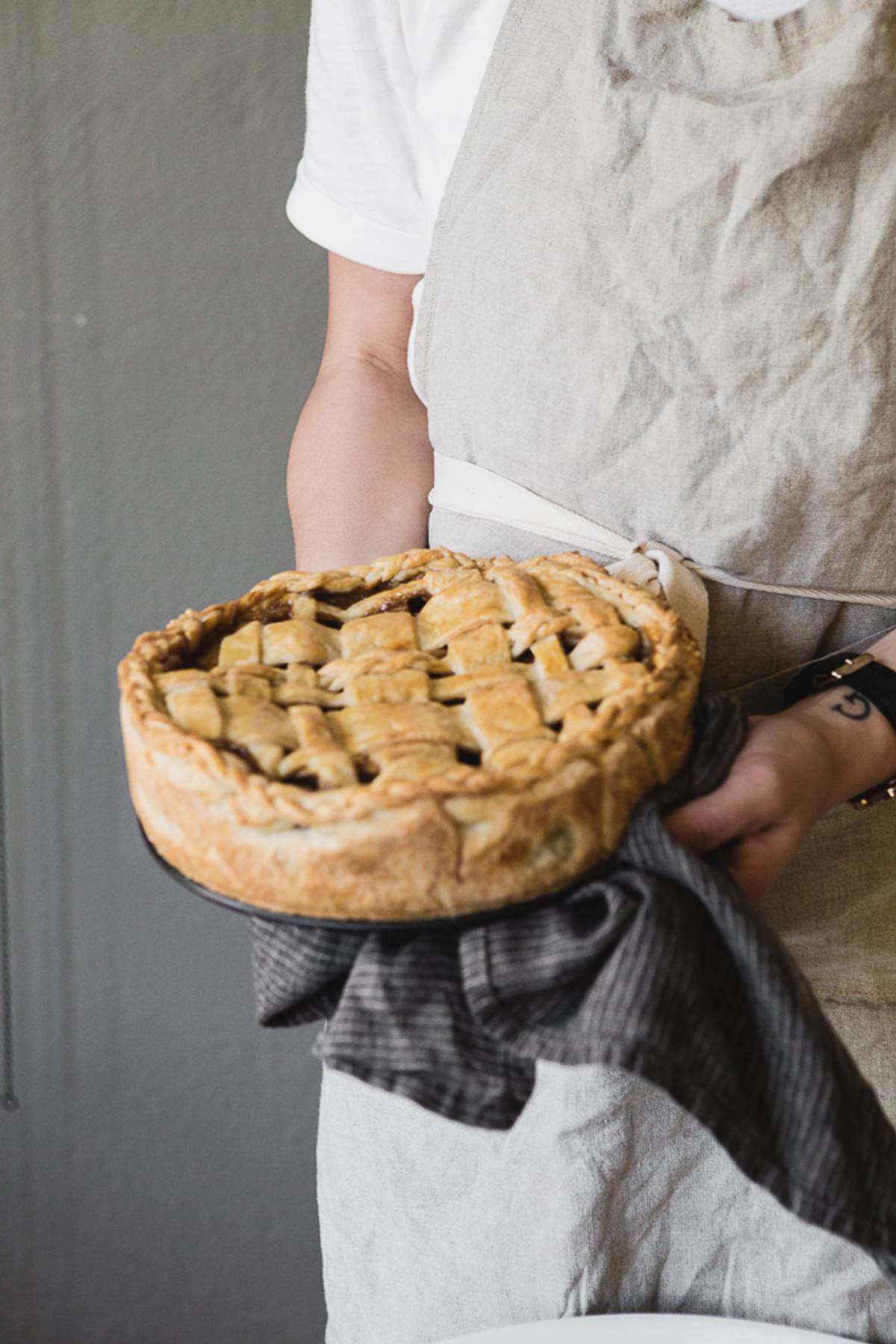 a person holding and apple pie with a linen