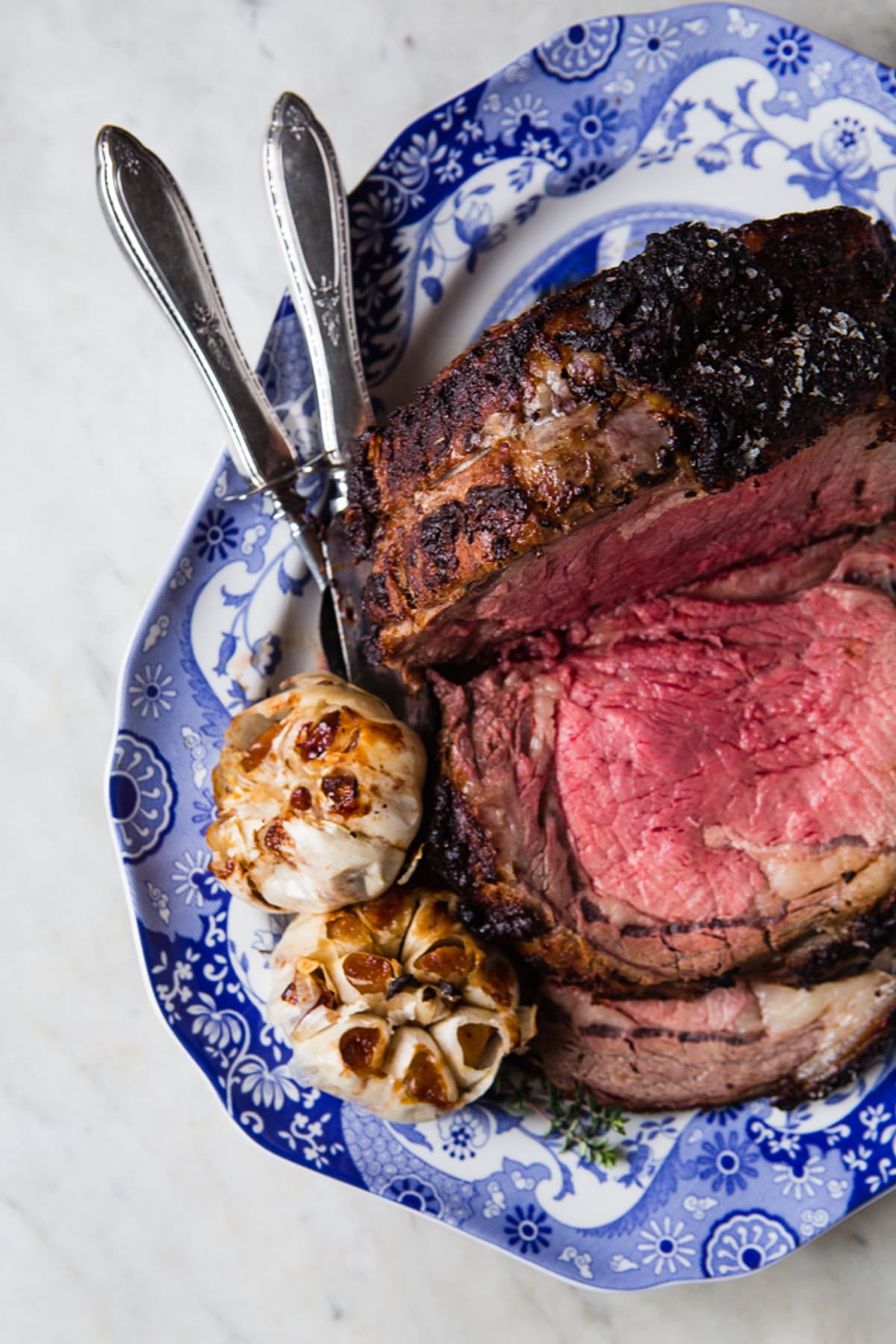 Prime Rib with Roasted Garlic and Horseradish Cream Sauce on a platter with serving fork