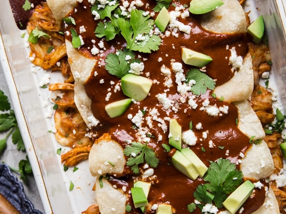 simple chicken mole enchiladas in a baking dish with avocado