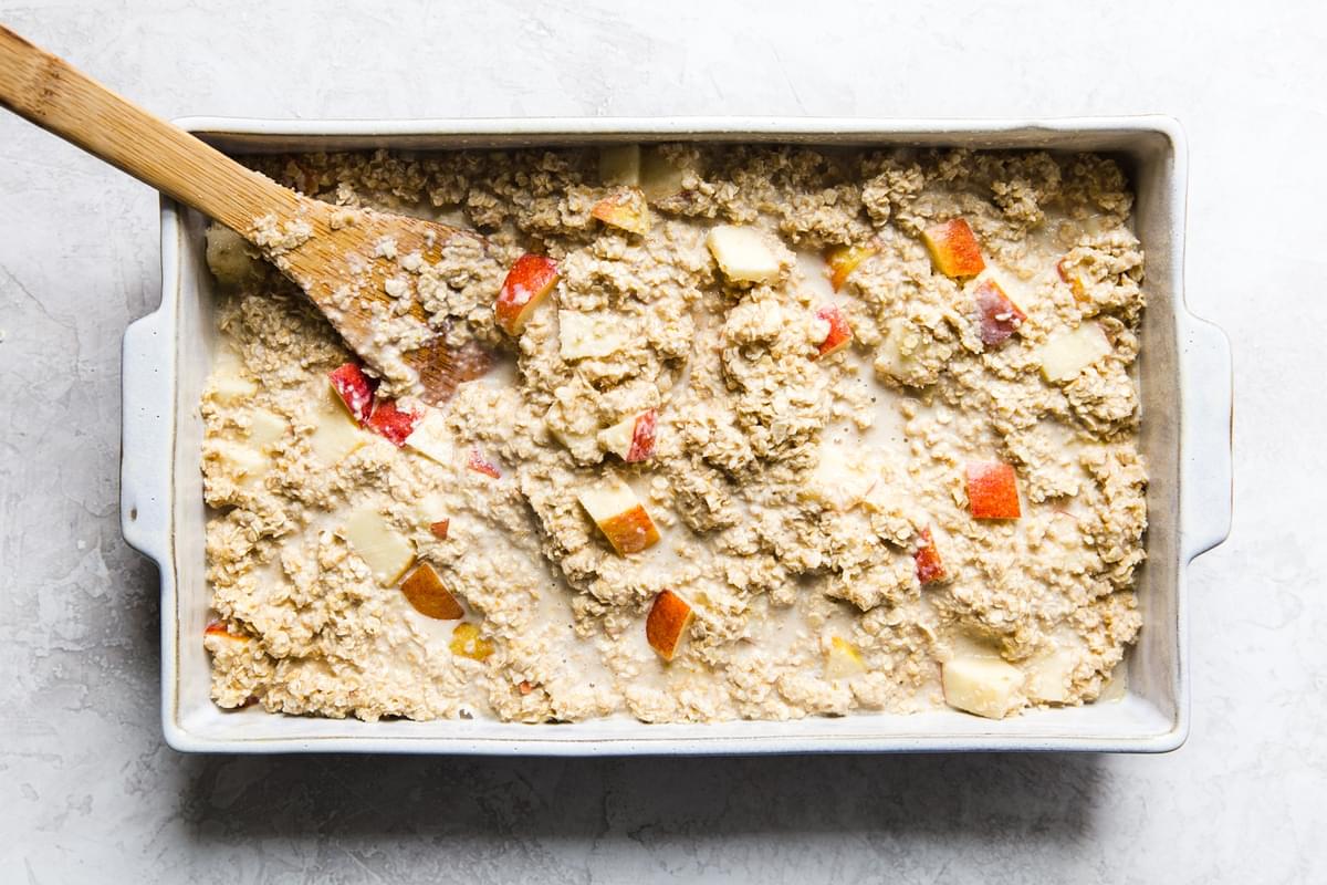 Baked Oatmeal With Apples being stirred in a 9x13 baking dish