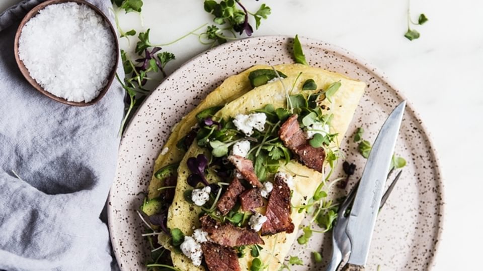 Avocado, Chèvre and Bacon Omelette on a plate with finishing salt in a small bowl