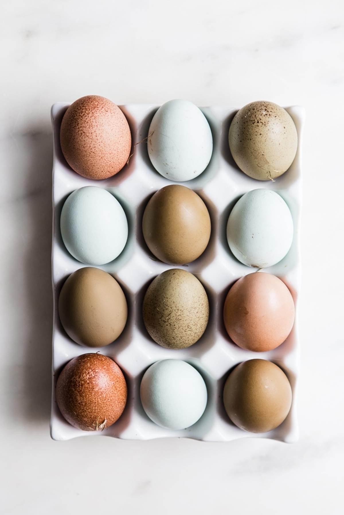 a dozen eggs in a ceramic white carton