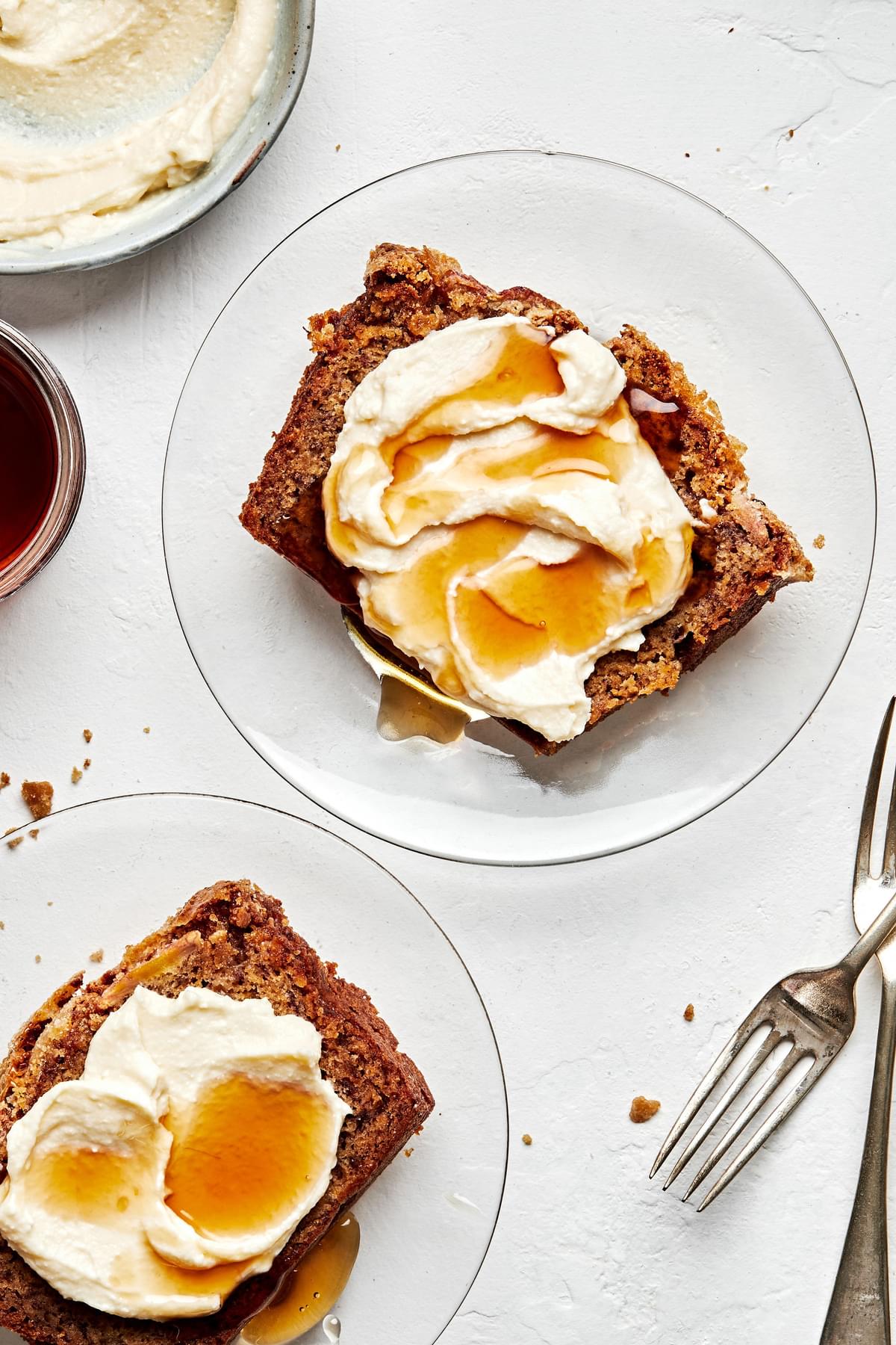 slices of the best homemade banana bread on plates slathered with maple mascarpone and a drizzle of extra maple syrup