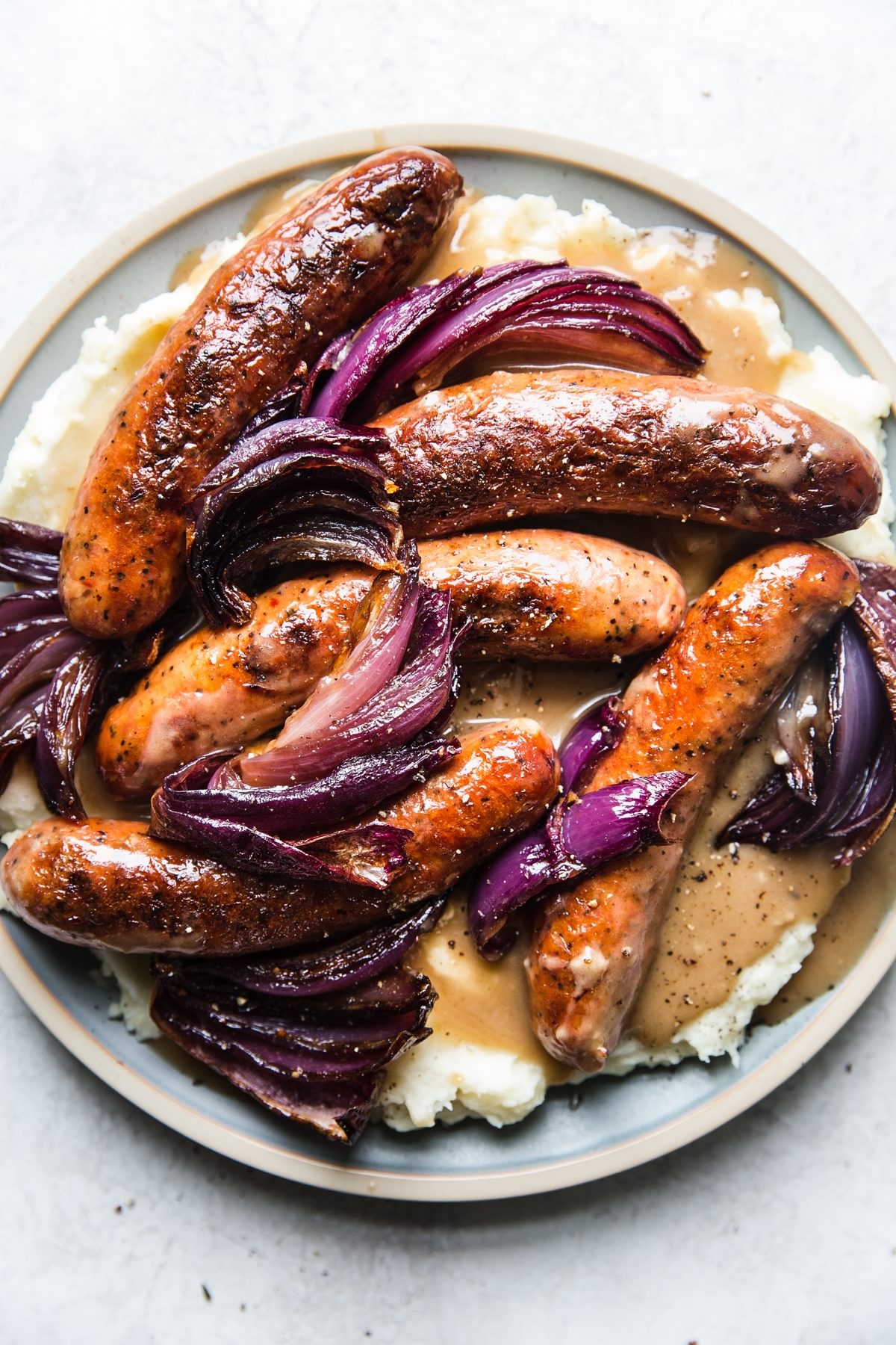 Bangers and mash with gravy and caramelized red onions on a plate