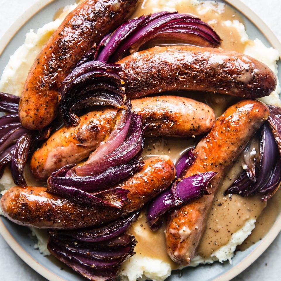 Bangers and mash with gravy and caramelized red onions on a plate