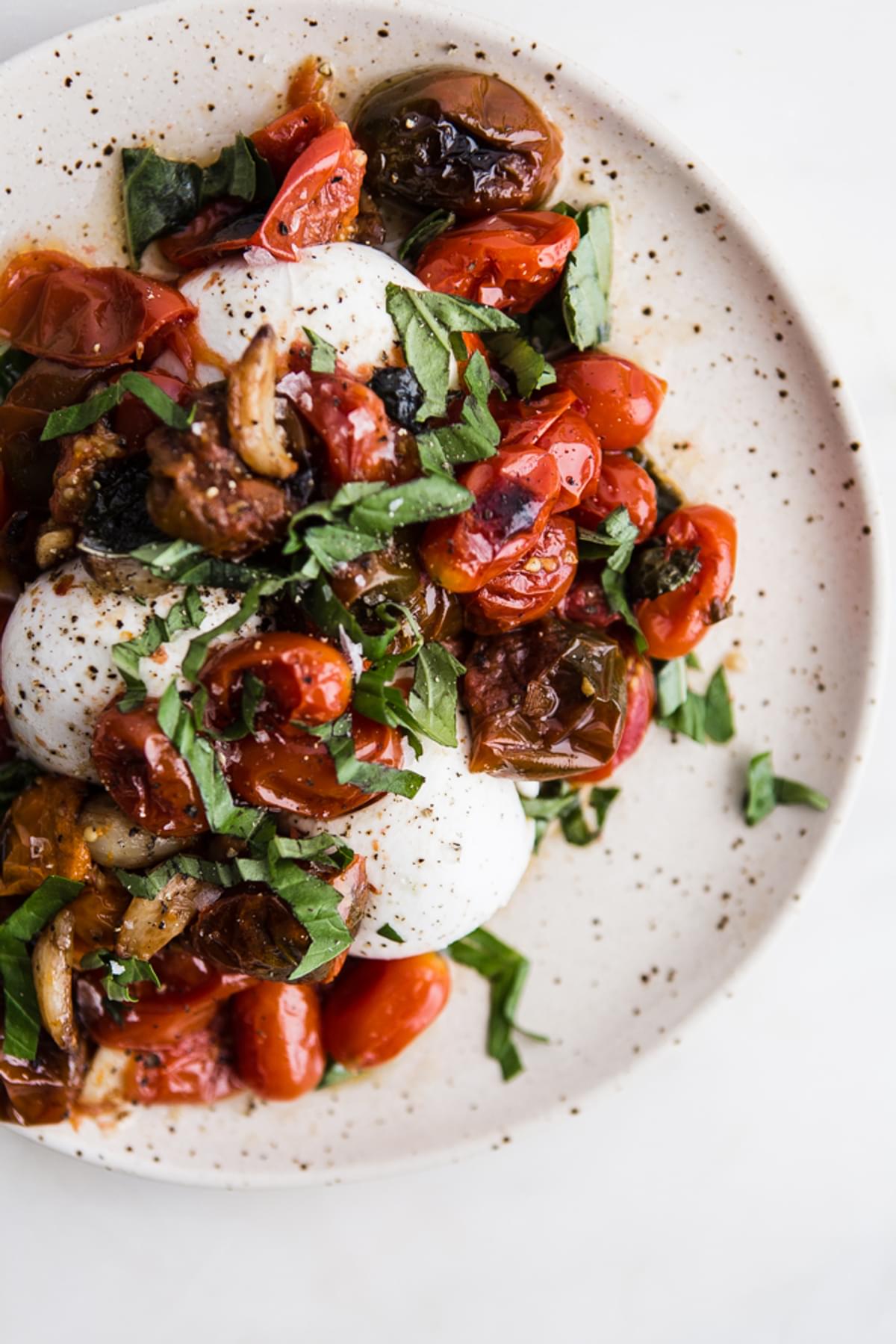 Braised Tomatoes with Burrata and basil on a plate
