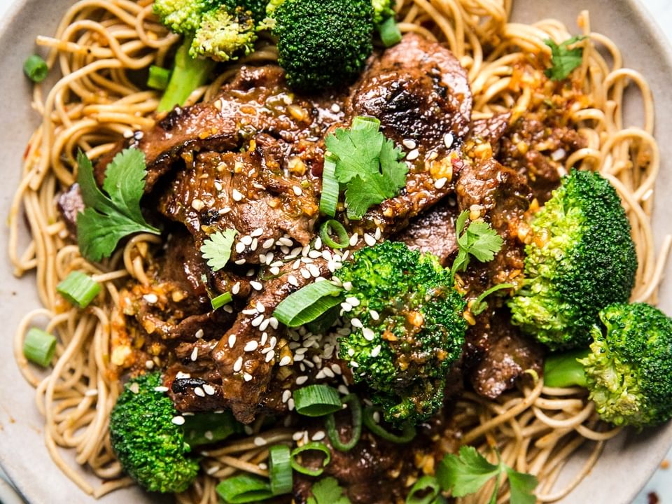 Broccoli and beef soba noodles in a bowl with sesame seeds